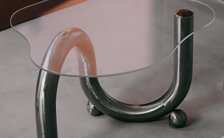 Stół w stylu industrialnym, minimalistycznym z metalową podstawą i szklanym blatem.
