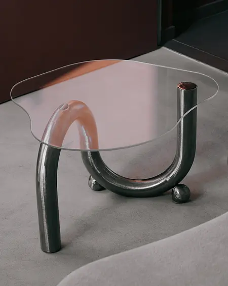 Stół w stylu industrialnym, minimalistycznym z metalową podstawą i szklanym blatem.