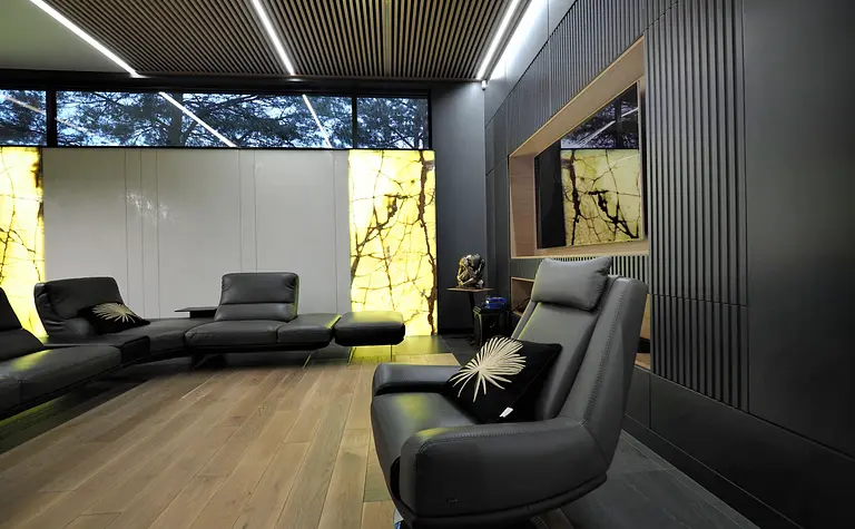 Nowoczesny salon z czarnymi meblami i drewnianą podłogą, z dużymi oknami.