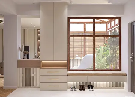 Nowoczesny przedpokój z beżowymi meblami i dużym oknem, roślinami i szafą.