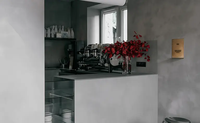 Nowoczesna kuchnia z betonowymi ścianami, minimalistycznymi meblami i industrialnymi akcentami.