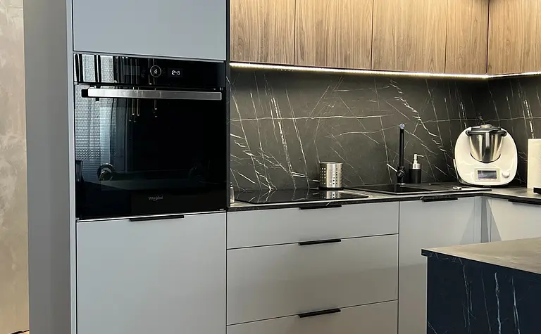 Nowoczesna kuchnia w stylu soft minimalizm z szarymi meblami i drewnianymi detalami.