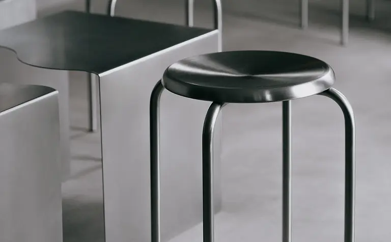 Nowoczesne wnętrze z metalowymi stołkami i minimalistycznym stołem w industrialnym stylu.
