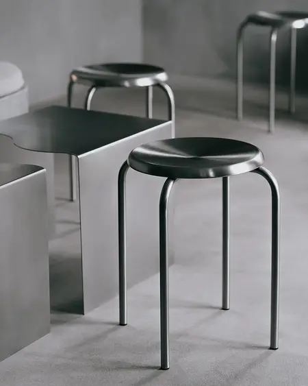 Nowoczesne wnętrze z metalowymi stołkami i minimalistycznym stołem w industrialnym stylu.