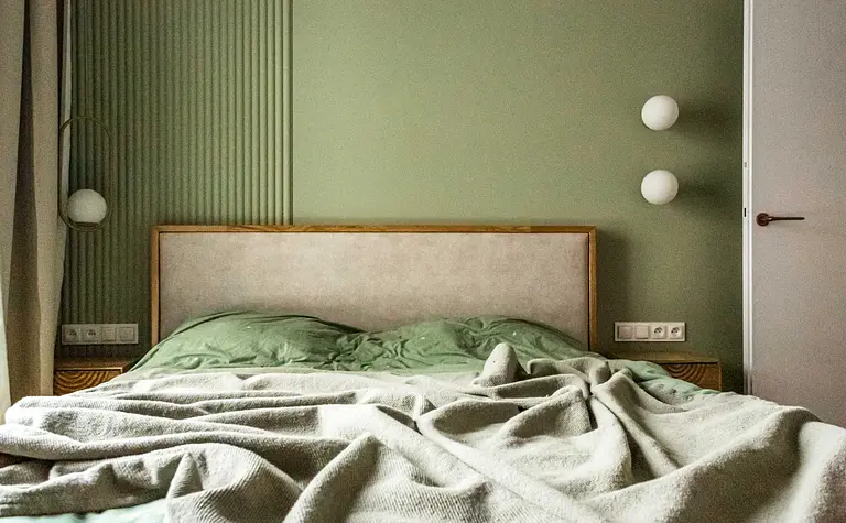 Sypialnia w stylu nowoczesnym i soft minimalizm z zielonymi ścianami i drewnianym łóżkiem.