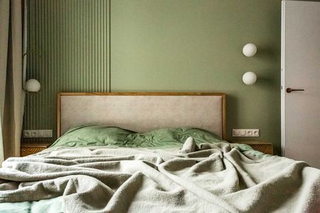 Sypialnia w stylu nowoczesnym i soft minimalizm z zielonymi ścianami i drewnianym łóżkiem.