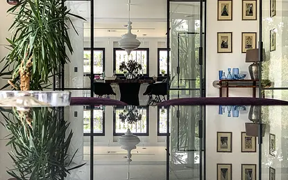 Wnętrze minimalistyczne z rośliną, szklanym stołem i elementami minimaluxe oraz quiet luxury.