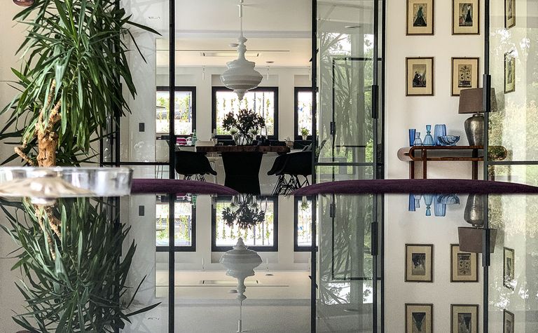 Wnętrze minimalistyczne z rośliną, szklanym stołem i elementami minimaluxe oraz quiet luxury.