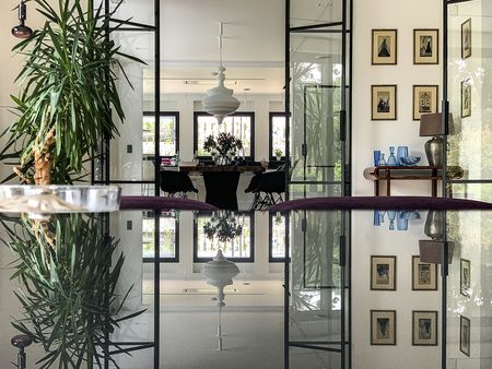 Wnętrze minimalistyczne z rośliną, szklanym stołem i elementami minimaluxe oraz quiet luxury.