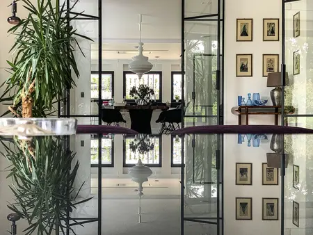Wnętrze minimalistyczne z rośliną, szklanym stołem i elementami minimaluxe oraz quiet luxury.