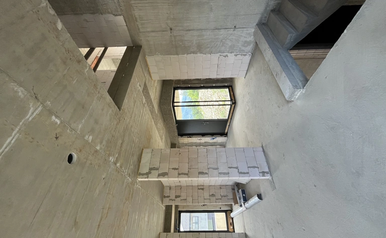 Wnętrze budynku z betonowymi ścianami i dużymi oknami, nowoczesny design.