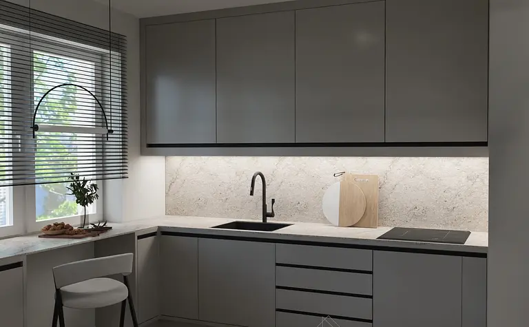 Kuchnia z nowoczesnymi szarymi meblami i białym blatem, z oknem i rośliną.