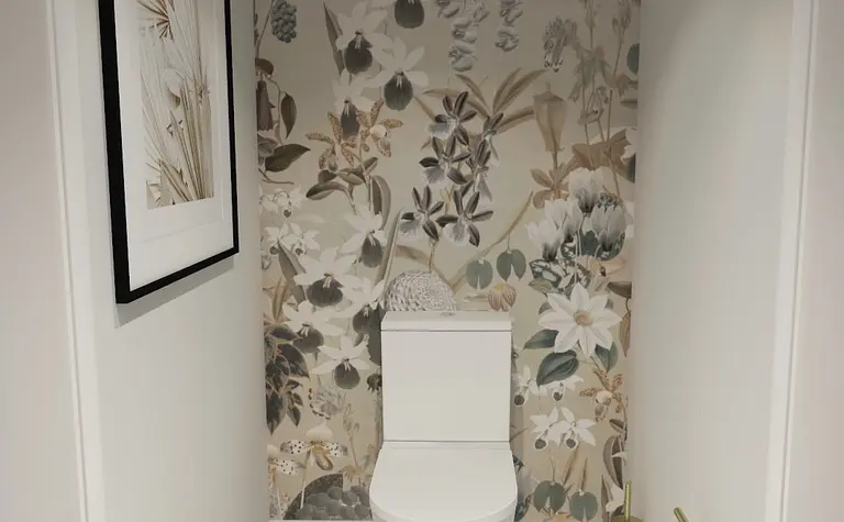 Toaleta z białą ceramiką, kwiecistą tapetą w stylu prowansalskim, czarno-biała podłoga.