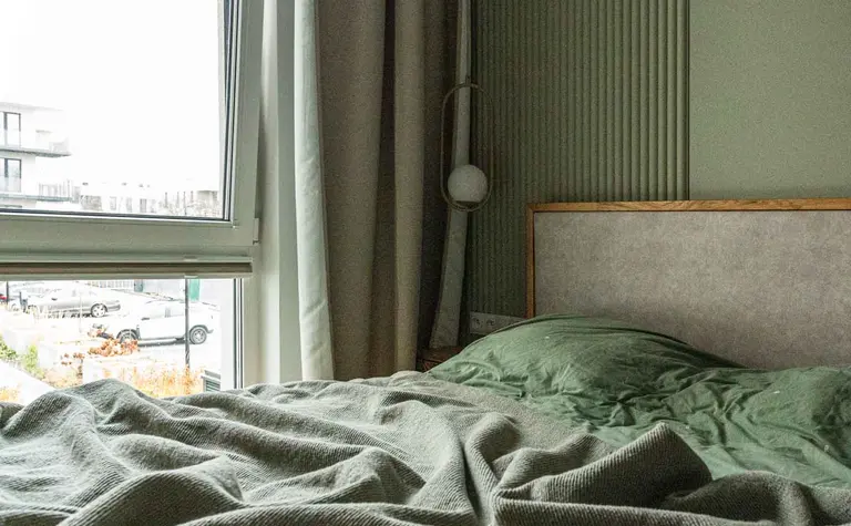 Wnętrze sypialni w stylu nowoczesnym i soft minimalizm z zieloną pościelą.