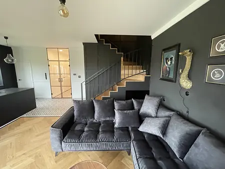 Wnętrze salonu w stylu art deco, industrialnym i rustykalnym z ciemnymi akcentami.