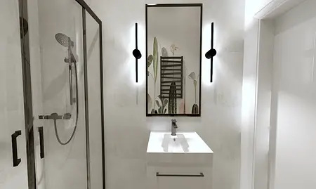 Współczesna łazienka z białą umywalką i prysznicem.