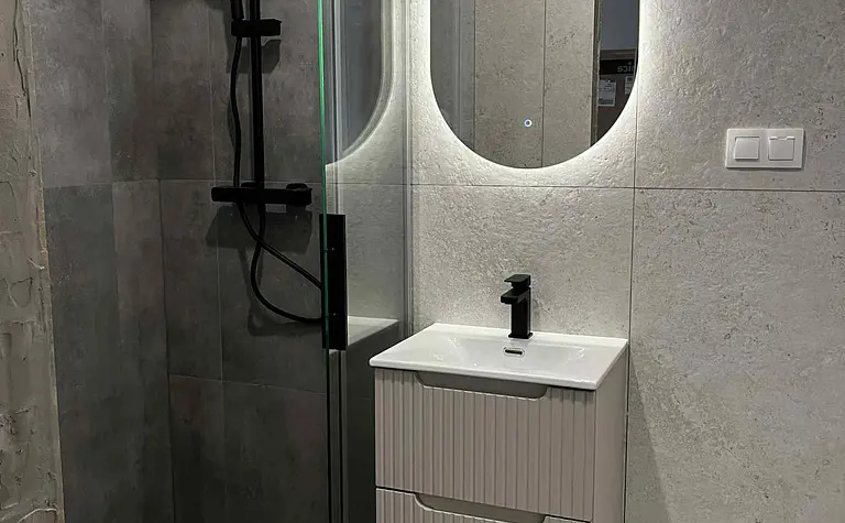 Nowoczesna łazienka z kabiną prysznicową i minimalistycznym umywalką w stylu glamour.