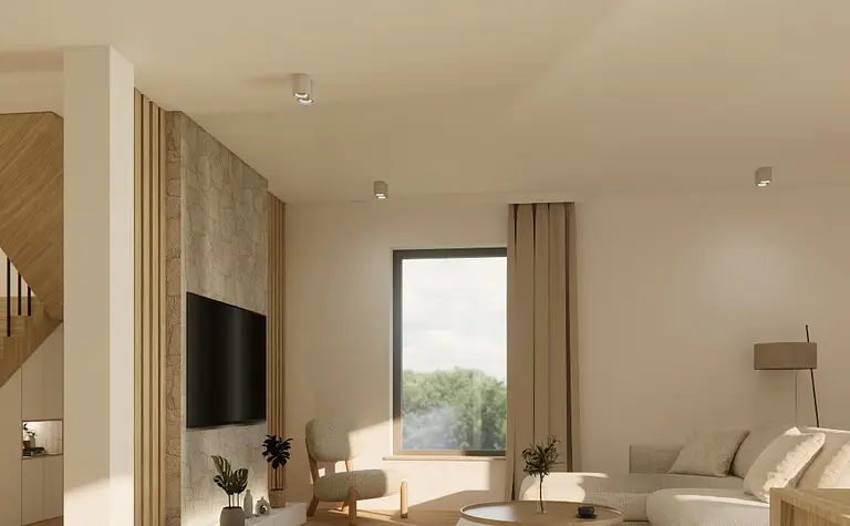 Jasny salon z beżową sofą, kamienną ścianą z telewizorem, oraz okrągłym, drewnianym stolikiem kawowym. Minimalistyczne oświetlenie i duże okno wpuszczają naturalne światło.