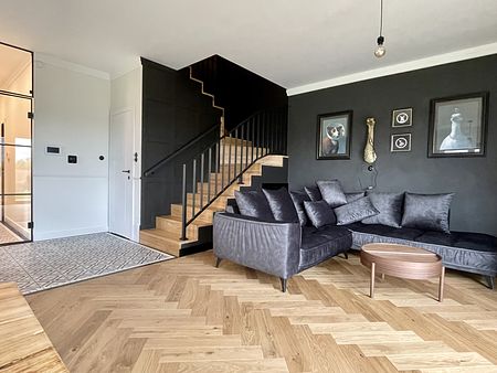 Wnętrze salonu w stylu art deco, industrialnym i vintage z ciemnymi ścianami i drewnianą podłogą.