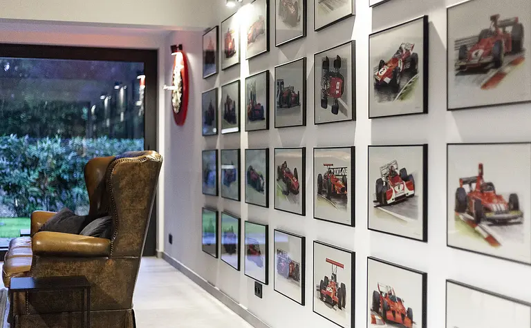 Wnętrze z brązowym fotelem, galerią zdjęć wyścigów, minimalistyczny i quiet luxury.