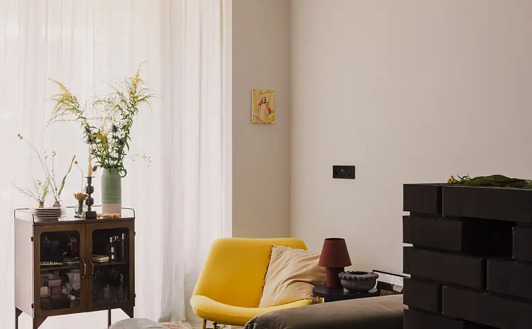 Współczesny salon z żółtym fotelem, szarym narożnikiem i roślinami.