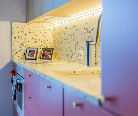 Kuchnia w stylu dopamine decor i vintage z różowymi meblami i jasnym blatem.