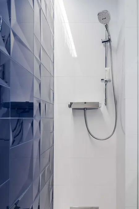 Kabina prysznicowa z niebieskimi i białymi płytkami w stylu minimalistycznym.