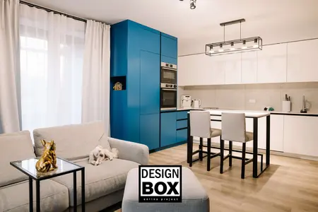 Wnętrze kuchni z niebieskimi meblami i białą zabudową, nowoczesny design.