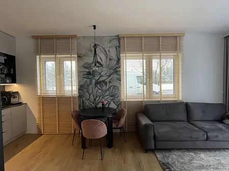Wnętrze jadalni z szarym sofą i okrągłym stołem w stylu eklektycznym i nowoczesnym.