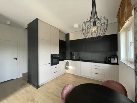 Kuchnia w stylu eklektycznym z czarnymi i białymi meblami oraz nowoczesnym oświetleniem.