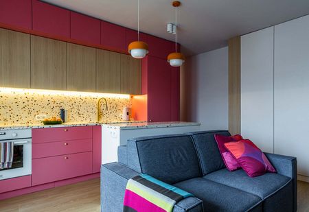Wnętrze kuchni w stylu dopamine decor i vintage z różowymi meblami.