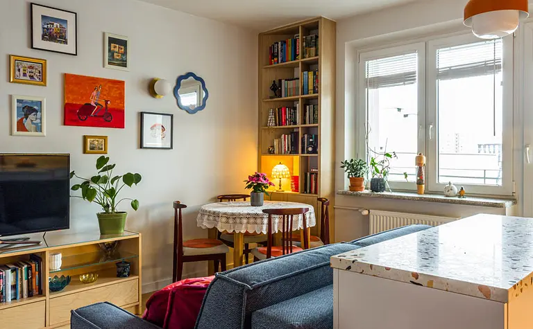 Wnętrze salonu z niebieską sofą, drewnianą półką, vintage i dopamine decor