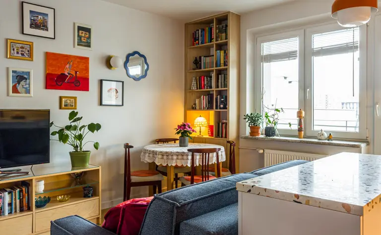 Wnętrze salonu z niebieską sofą, drewnianą półką, vintage i dopamine decor
