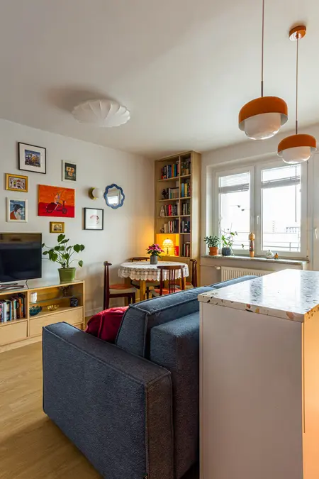 Wnętrze salonu z niebieską sofą, drewnianą półką, vintage i dopamine decor