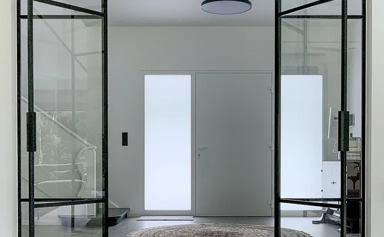 Przestronny przedpokój z przeszklonymi drzwiami, minimalistyczny styl, minimaluxe, quiet luxury.