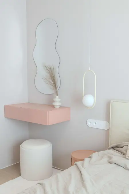 Sypialnia w stylu art deco i boho z różowym stolikiem i dekoracyjną rośliną.