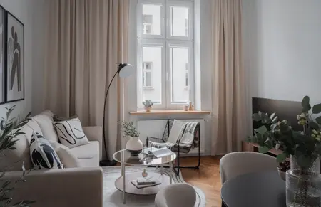 Nowoczesny salon w stylu skandynawskim z beżowymi zasłonami i minimalistycznymi meblami.