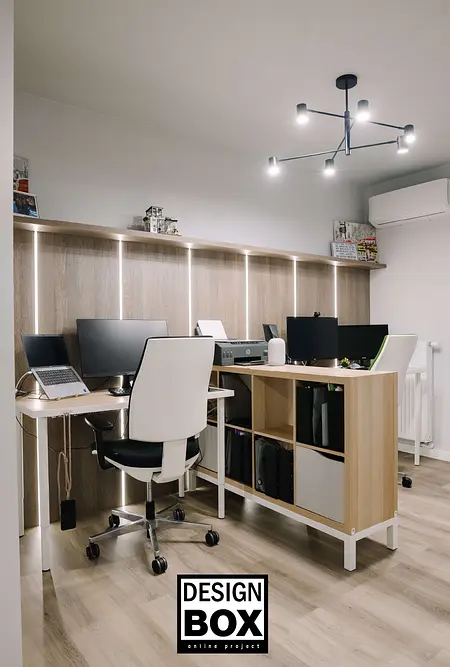 Biuro z jasnymi meblami i nowoczesnym oświetleniem, z komputerami i ergonomicznymi krzesłami.