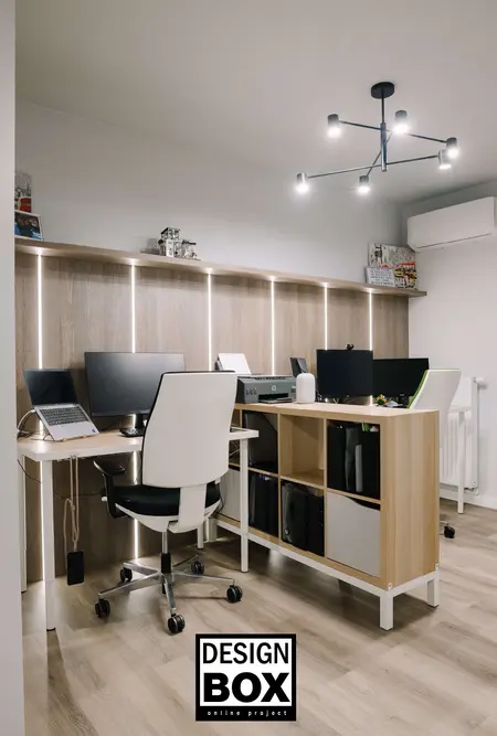 Biuro z jasnymi meblami i nowoczesnym oświetleniem, z komputerami i ergonomicznymi krzesłami.