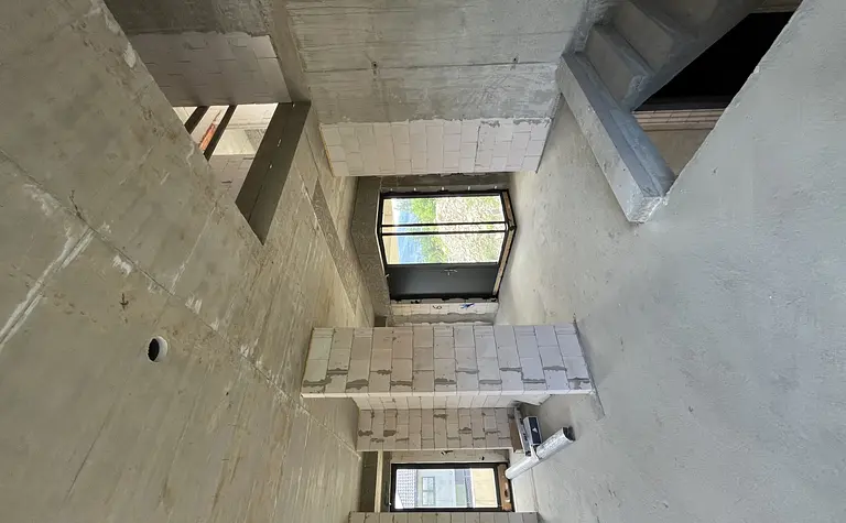 Wnętrze budynku z betonowymi ścianami i dużymi oknami, nowoczesny design.