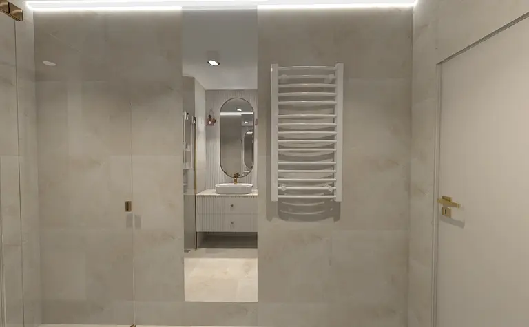 Wnętrze łazienki z białymi płytkami, umywalką i lustrem.