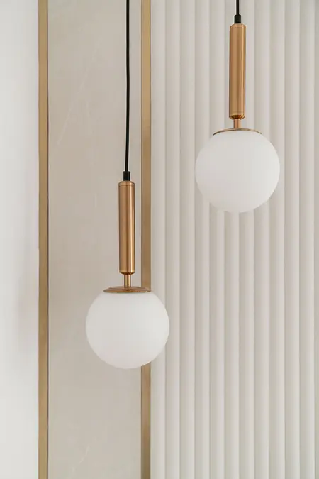 Lampa wisząca w białym wnętrzu z metalowymi akcentami.