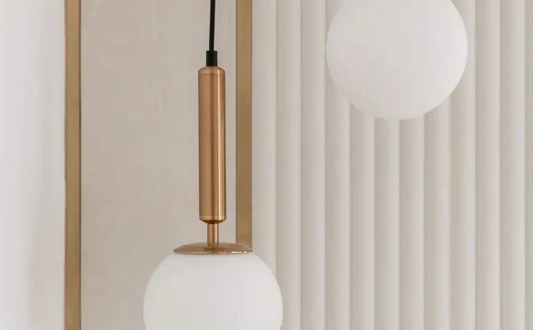 Lampa wisząca w białym wnętrzu z metalowymi akcentami.