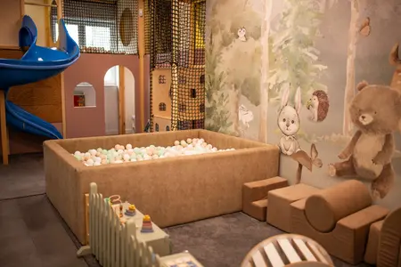 Pokój dziecięcy z placem zabaw, kolorowymi kulkami oraz muralem w stylu art deco i nowoczesnym.