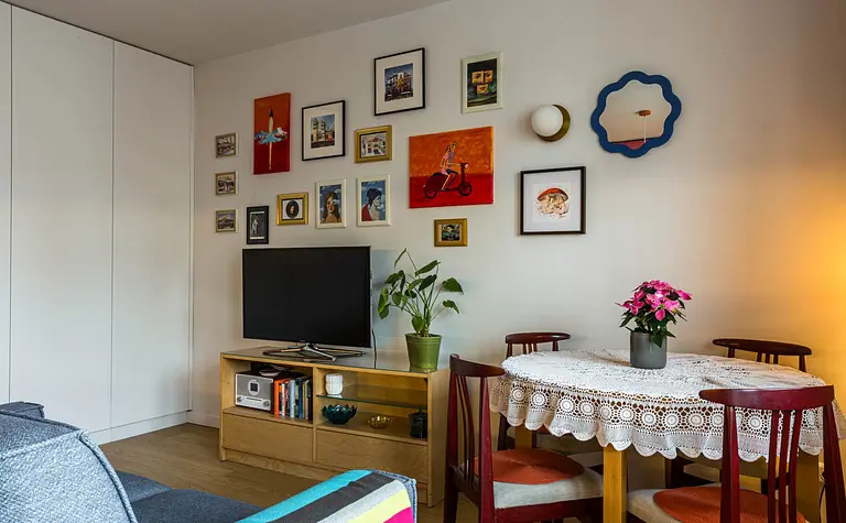 Wnętrze salonu z telewizorem, okrągłym stołem, styl dopamine decor i vintage.