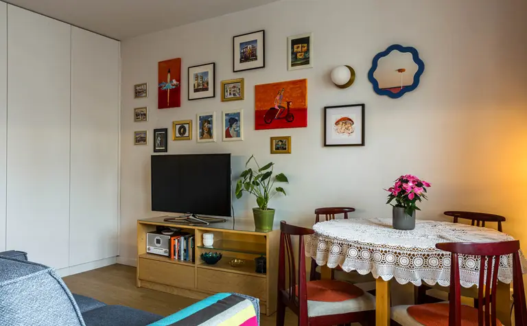 Wnętrze salonu z telewizorem, okrągłym stołem, styl dopamine decor i vintage.