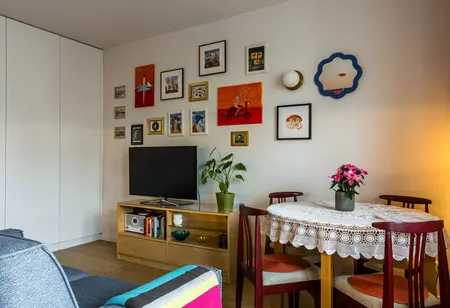 Wnętrze salonu z telewizorem, okrągłym stołem, styl dopamine decor i vintage.