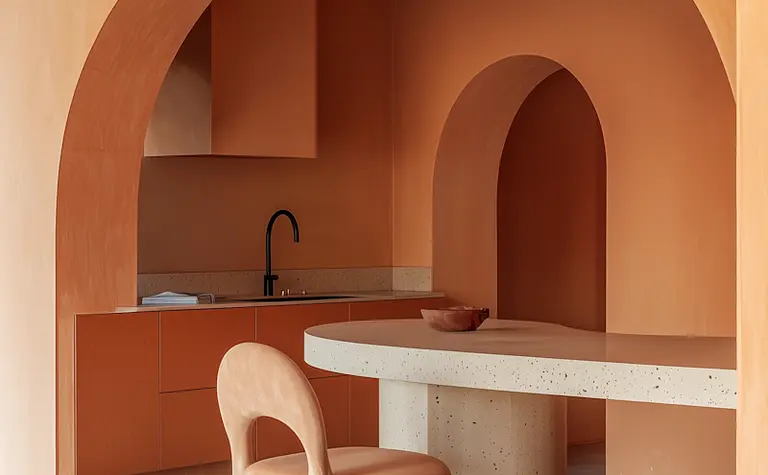Wnętrze kuchni z pomarańczowymi ścianami i nowoczesnym blatem.