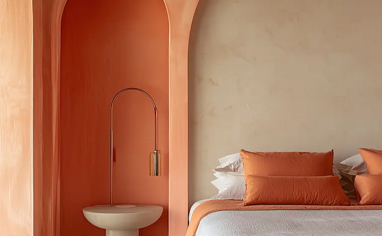 Wnętrze sypialni z pomarańczowymi poduszkami i nowoczesnym oświetleniem.