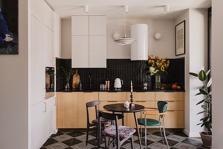 Kuchnia z białymi meblami, czarnym blatem i kolorowymi kwiatami, współczesny styl